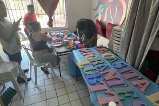 People crafting colorful letters at a table.