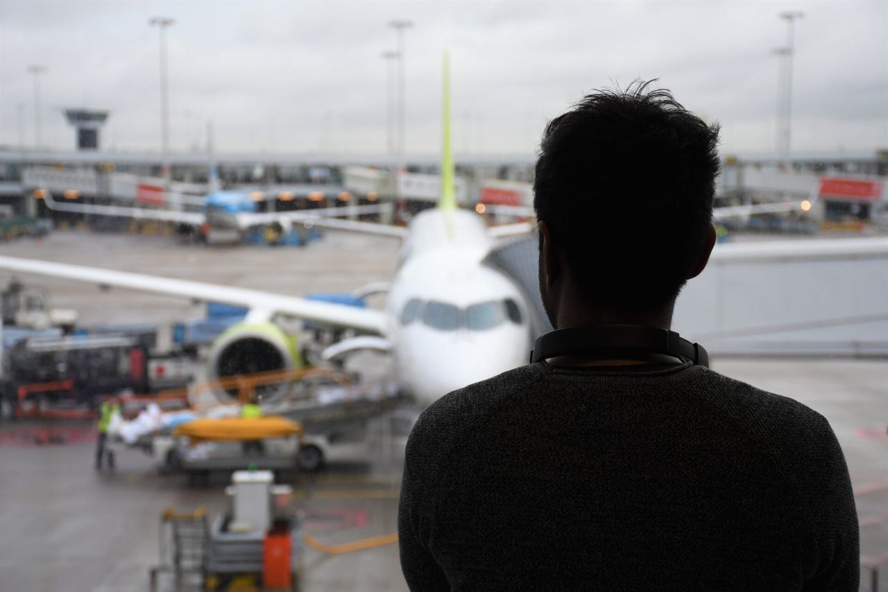 Person viewing an airplane through an airport window.