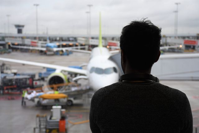 Person viewing an airplane through an airport window.