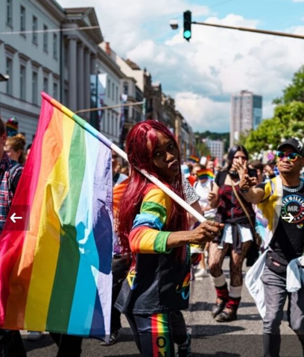 Person holding a rainbow flag while marching in a Pride parade.