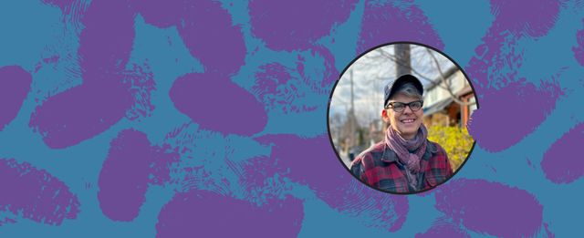 Person smiling outdoors wearing glasses, a cap, and a scarf.