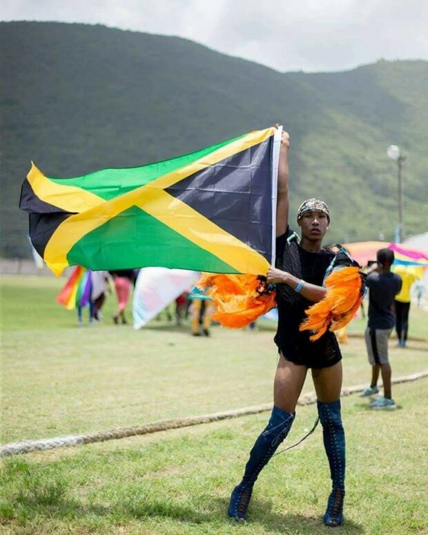 Person wearing black outfir and holding the Jamaican flag
