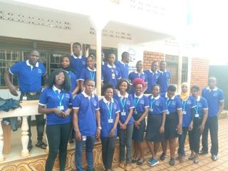 Group of people in matching blue shirts posing outside a building.