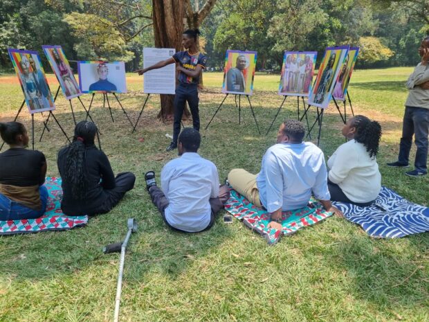 Outdoor workshop where a facilitator presents portrait boards to a small seated group in a park.