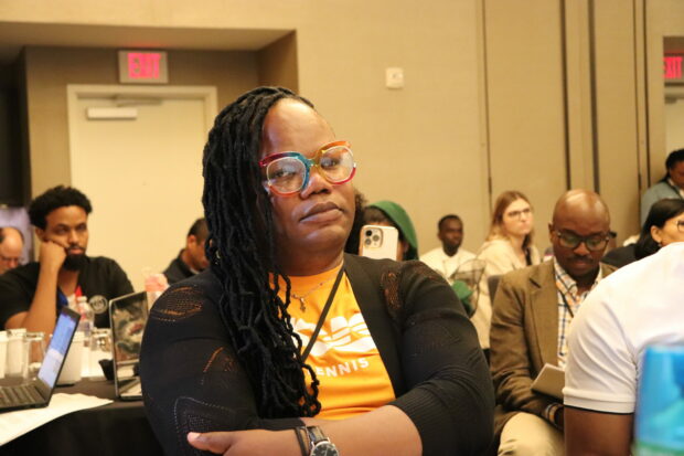 Person with glasses sitting in a conference audience.