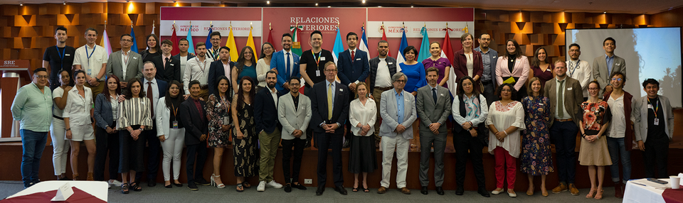 Large group photo of attendees at an LGBTIQ+ regional integration meeting with multiple country flags.
