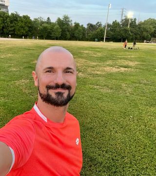 Person in an orange shirt against a grassy background with trees.