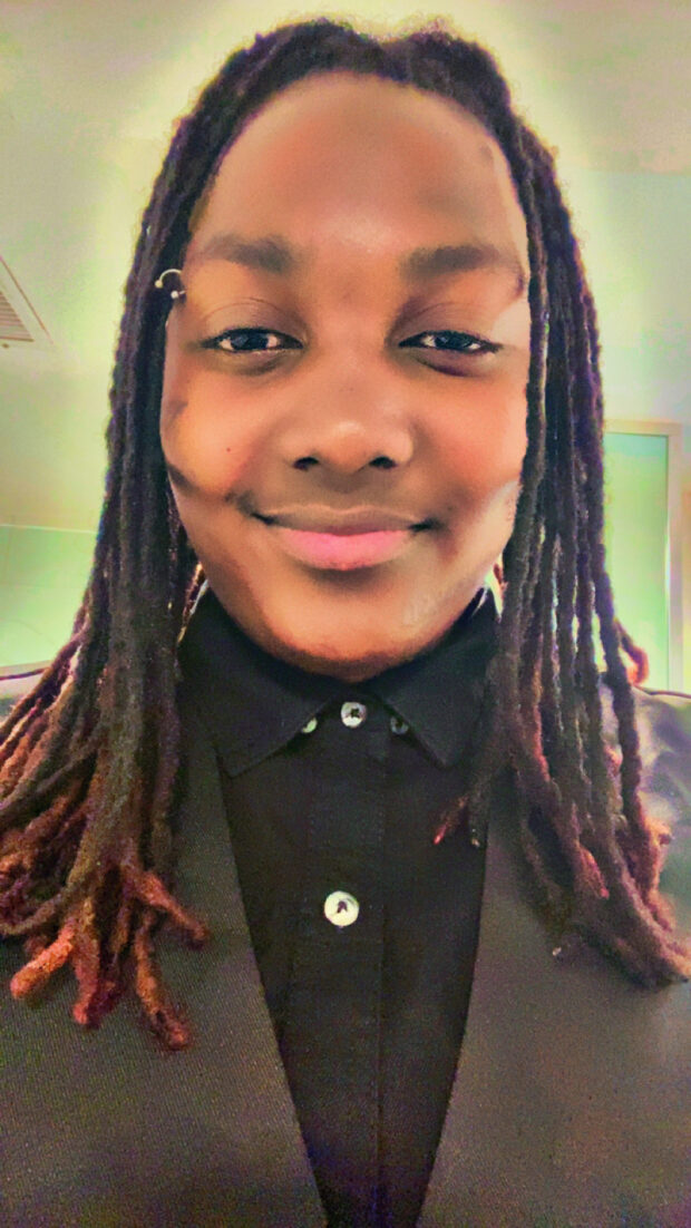 Person smiling wearing a black collared shirt.