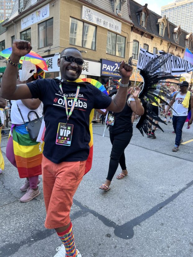 Person smiling and marching in a Pride parade.