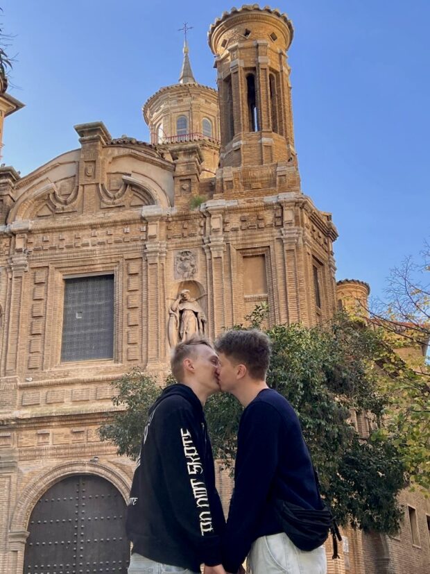 Couple kissing in front of a historic brick building.
