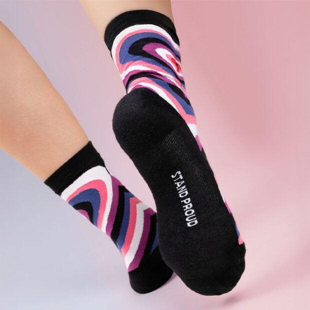 Feet wearing black socks with pink, purple, and blue swirls.