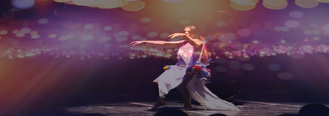 Person dancing on a stage with colourful lights.