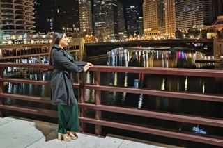 Person standing by a city river at night.