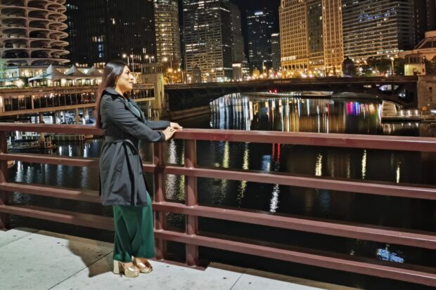 Person standing by a city river at night.