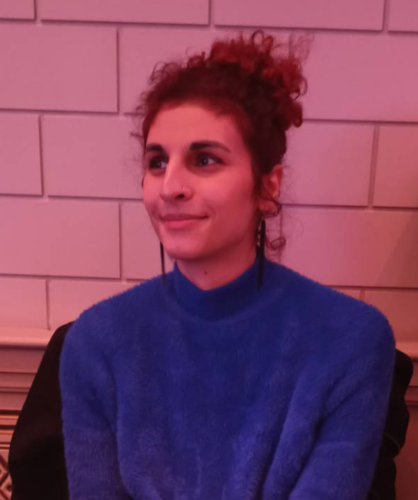 Person in a blue sweater sitting indoors with a calm expression.