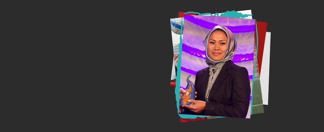 Person wearing a blazer smiling while holding an award.
