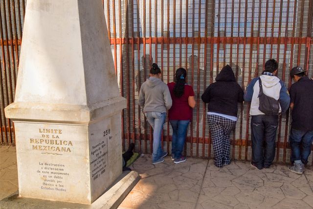 Individuals standing by a border gate
