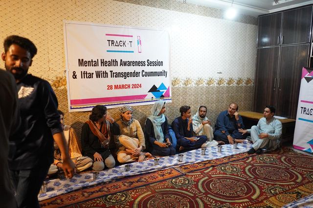 People sitting on floor at a community mental health and iftar event, with a banner behind them.