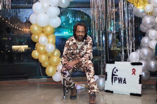 Person seated at an event decorated with gold and white balloons.