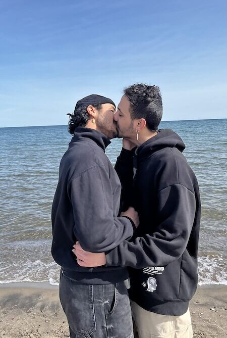 Two people kissing by the ocean.