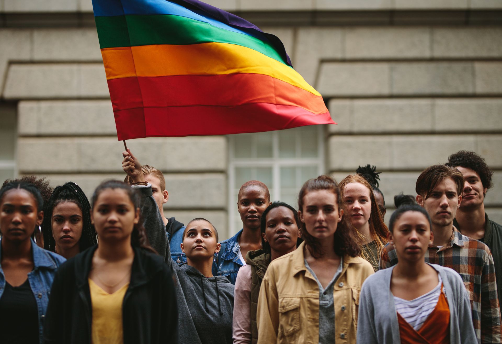 Diverse group of individuals with rainbow flag.