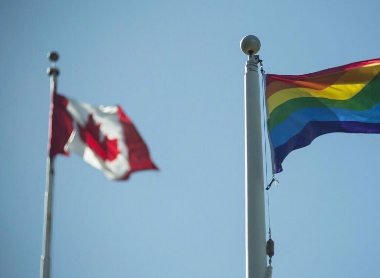 Canadian flag beside a pride flag.