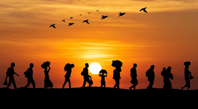Silhouettes of people walking across a sunset